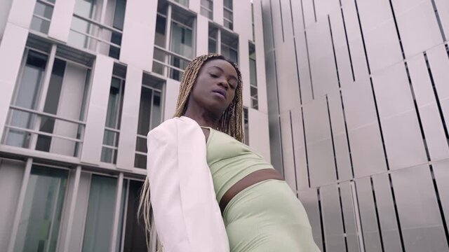 Woman dancing in the street. A young black woman moves rhythmically. She has long hair and braids. Pretty dancer. The girl's facial expressions change shape.
