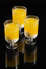 Yellow trifle cakes in glass on the black background