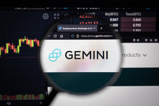 Gemini crypro exchange logo on a website with blurry stock market developments in the background, seen on a computer screen through a magnifying glass