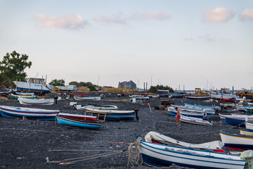 Obraz premium Stromboli island (Aeolian archipelago), Lipari, Messina, Sicily, Italy, 08.21.2021: view of the village with many boats on the black lava beach.