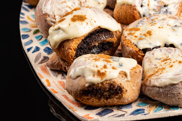 Poppy seeds buns on the ceramic plate on the black background