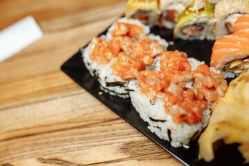 Hand Waiter holding Set Delicious fresh Sushi slate plate, Japanese raw fish in traditional restaurant. Philadelphia fresh Rolls served on plate in sushi bar. waiter in gloves holds sushi rolls
