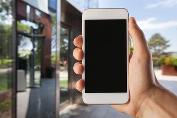 Human hand holding smartphone with white blank empty screen mockup, using smart at home