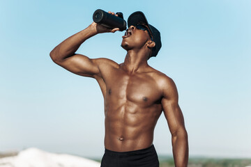 African American man drinking water bottle, athlete resting after outdoor workout