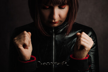 Close Up of Woman with black latex dress and Hand Cuffs. - obrazy, fototapety, plakaty