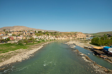Waters of the Tigris river as it passes through the city of Hasankeyf with a cliff full of caves in an area of Mesopotamia - obrazy, fototapety, plakaty