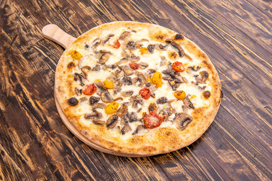Pizza italiana con receta de tartufata, con setas confitadas, aceite de oliva, tomates cherry rojos y amarillos, alcaparras, anchoas, aceitunas negras, trufa negra y ajo