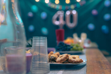 Obraz na płótnie Canvas Collection of cookies and other food on a party table at a birthday event with visible baloons in the background. Focus on cookies.