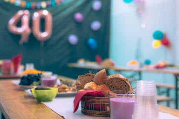 Collection of cookies and other food on a party table at a birthday event with visible baloons in the background. Focus on bread.