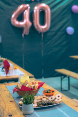 Collection of cookies and other food on a party table at a birthday event with visible baloons in the background. Focus on cookies and bread.