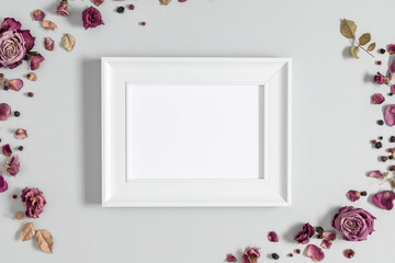 White blank frame mockup and dry flowers and dried berries on a gray background. Flat lay, top...