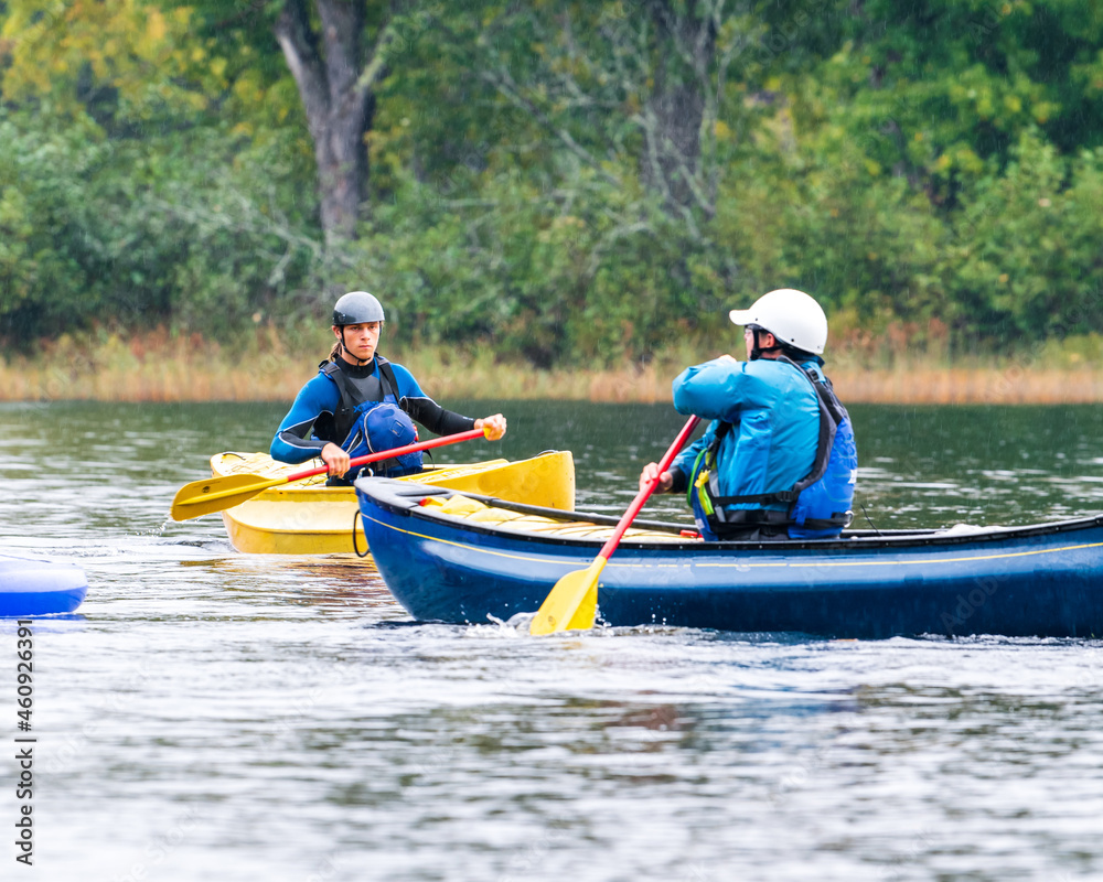 Wall mural two canoeists practice paddle strokes on a rainy fall day during a “moving water” paddling course. a