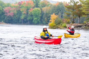 Fototapeta premium A solo canoeist practices stroke techniques on a rainy fall day as part of a “moving water” paddling course. Shot on the Madawaska River an iconic paddling destination in Eastern Ontario, Canada.