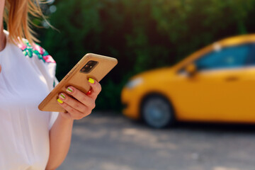 Smartphone or phone in female hands on a blurred background of a yellow taxi service car