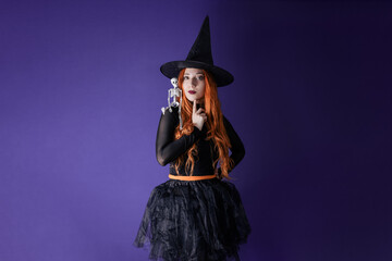 GIRL DRESSED AS A WITCH THINKING WITH SKELETON TOY. HALLOWEEN