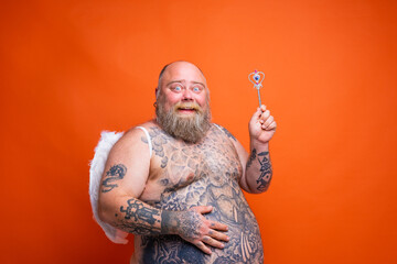 Fat happy man with beard ,tattoos and wings acts like an magic fairy