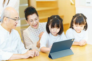 タブレットPCを操作するシニア夫婦と孫たち