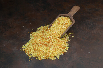 Dry bulgur wheat grains with a spoon close up