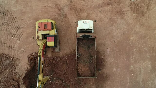 Excavator taking earth and placing it on a dump truck in a construction in Brazil. Top view