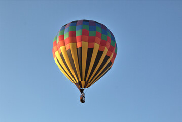 Colorful hot air balloon in flight with blue skies in the background