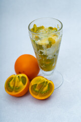 glass of fresh lulada surrounded by lulos on a marble background