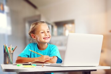 Young girl focused studying online class, writing notes with teacher video call conference