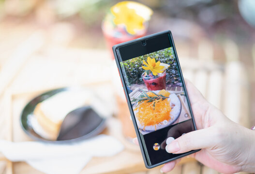 Female hand uses the Mobile Phone take photo with the Thai dessert for recommend and share to social media.