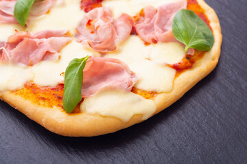 Traditional italian pizza with ham mozzarella and  basil