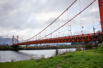 Suspension bridge in Aysén, Southern Chile. Patagonia. Painted in red in front of the mountain.