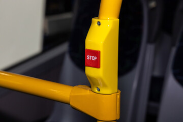 Red STOP button with Braille lettering on the bus handrail. Button to signal the driver of public...