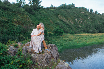 Romantic inloved couple sitting on rocks by the river.