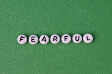 Alphabet beads with text FEARFUL isolated on a green background