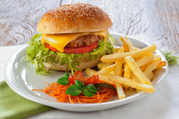 Cheeseburger com salada e batatas fritas sobre fundo de mesa.