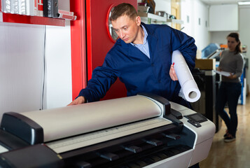 Repairman changes paper roll in plotter. High quality photo
