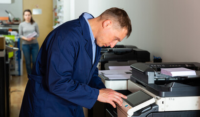 Obraz premium Service engineer pulls the paper from the machine. High quality photo