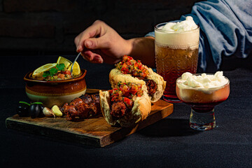 person taking a spoonful of pebre from the bowl to put it on his choripan, accompanied by a large...