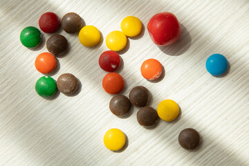 round multi colored chocolates on a wooden table, sweet texture, food in studio