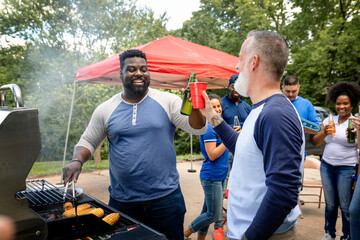 Manning the grill at a tailgate party - obrazy, fototapety, plakaty
