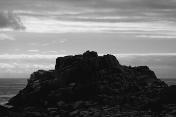 piedras acumuladas y el mar de fondo en blanco y negro