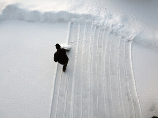 op down view of man shoveling a second time because of continuously falling snow.  © styxclick