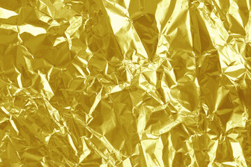 Shiny gold foil texture background, pattern of yellow wrapping paper with crumpled and wavy.