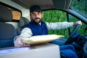 Delivery driver driving van with parcels on seat outside the warehouse to the client.