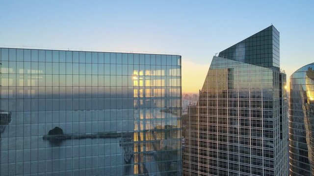 Cinematic aerial slow panning at the top of modern skyscrapers office buildings with translucent and reflective glass window at sunset golden hours, close up view, downtown Buenos Aires, Argentina.