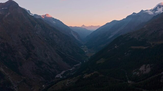 Dolly forward drone shot through Swiss mountain valley at sunrise Zermatt