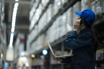 Warehouse worker using walkie-talkie with laptop in warehouse