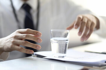 Cropped image of businessman with glass of water on desk