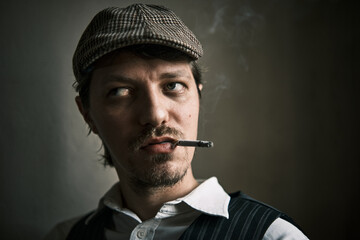 Young guy smoke a cigarette, dressed in a retro style