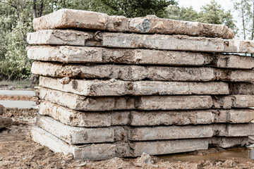 Old reinforced concrete road slabs stacked on a construction site for later use. Temporary road surface.