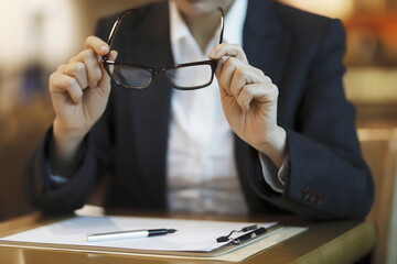 Businesswoman holding eyeglasses at desk