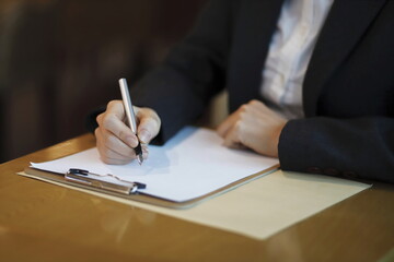 Businesswoman writing on clipboard at desk	
